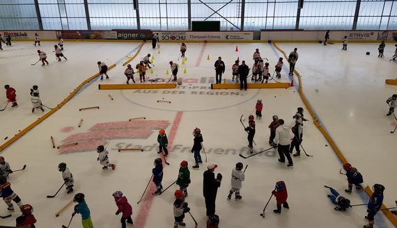 Ein Bild der Eishalle mit vielen kleinen Kindern auf dem Eis. Viele Kinder versuchen ihre ersten Schritte auf dem Eis zu machen.